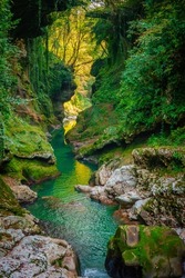 Calm river flowing through ravine with green walls on sunny summer day in highlands at Martvili Canyon, Georgia