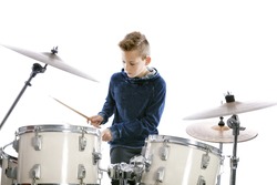 teenage boy behind drum kit in studio against white background