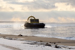 Hovercraft flying above water. Air cushion sailing near beach. Yellow hover craft under way.