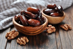 Dates fruit in a wooden bowl closeup on wooden background
