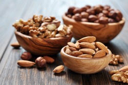 Almonds, walnuts and hazelnuts in wooden bowls  on wooden background