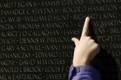a finger points out a name inscribed at the Vietnam Veterans Memorial in Washington, DC