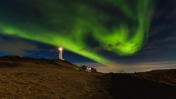 The beautiful northern lights or aurora borealis in Iceland with lighthouse near Keflavik named Reykjanes Lighthouse.