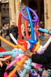 Closeup of a balloon seller with multi colored balloons in the shape of a sword and heart during the Carnival in Bologna city, Emilia Romagna, Italy, Europe.