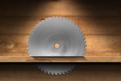 Closeup of a metal circular saw blade that cutting a plank of wood. Carpentry concept