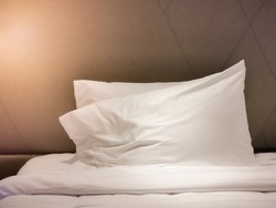 Luxury leather bedhead and white pillows with warm light.