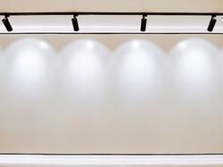 Photo of white empty wall copy space, Gallery Interior with illuminated black track light on cieling for stock.