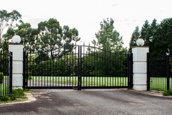Black metal wrought iron driveway property entrance gates set in brick 