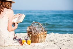 Summer - picnic by the sea. Girl in Hat and basket for a picnic with buns, apples and juice. 