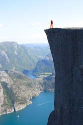 girl hiker standing on Preikestolen and looking at the mountains. Preikestolen -famous cliff at the norwegian mountains