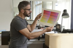 Printing industry: Graphic designer checks the color with color swatch.