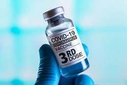 doctor with Coronavirus vaccine bottle with the name of the Third vaccine on the label. COVID-19 Vaccine Vial for vaccination tagged with 3rd dose