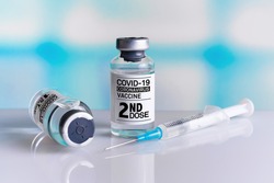 Two COVID-19 Vaccine Vials tagged with 1st and 2nd dose for vaccination of patients. Vaccine bottles identified with first and second dose labels for covid-19 immunization