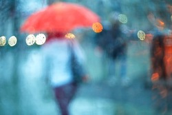 Young girl with an umbrella through a glass with rain drops. Blur bokeh, defocused background