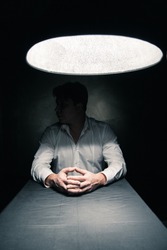Man in a dark room illuminated only by a light coming from a lamp no face seen