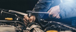Auto mechanic working on car engine in mechanics garage. Repair service. authentic close-up shot, banner size