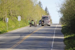 A large dump truck passes a farm tractor on a two lane road/Farm Vehicles and Road Traffic/A truck passes a farm tractor. 