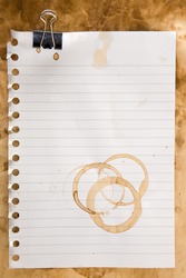 Paper from a notepad with coffee stains and clip