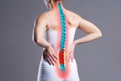 Pain in the spine, woman with backache on gray background, back injury, photo with highlighted skeleton