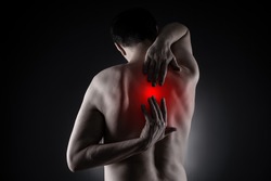 Pain between the shoulder blades, man suffering from backache on black background, painful area highlighted in red