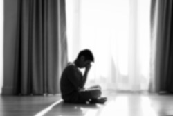 Blurry background Silhouette sad boy crying at window, black and white.
