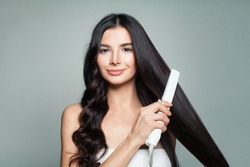 Attractive Woman with Curly Hair and Long Straight Hair Using Hair Straightener. Cute Smiling Girl Straightening Healthy Brunette Hair with Flat Iron.