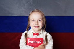 Learn russian language. Child girl student with book against the russian flag background