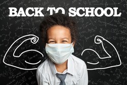 Happy child student in medical protective face mask on blackboard background