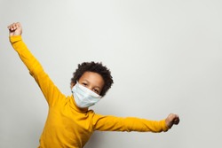 Portrait of funny black child boy in medical protective face mask having fun