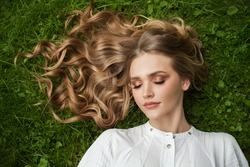Young blonde woman relaxing on green grass outdoor