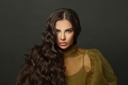 Gorgeous brunette model beauty portrait. Healthy woman with shiny dark wavy hair closeup on black studio wall background