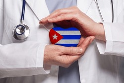 Cuban doctor holding heart with flag of Cuba background. Healthcare, charity, insurance and medicine concept