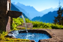 Water spring on Alps mountains background.