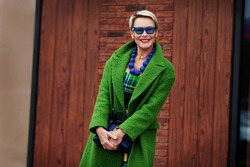 Portrait of smiling stylish woman wearing green coat with blue accessories. Colorful Trendy casual outfit. Happy model 45-50 years old with short fashionable haircut