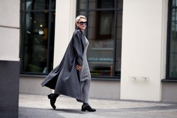 Elegant Mature woman walks city street , wears stylish clothes, gray wool coat, long dress, black shoes and glasses. Trending outfit