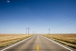 An empty rural highway with blue sky horizon