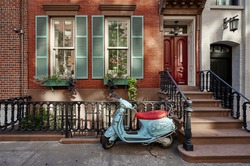 a brownstone building with a vintage scooter in a famous neighborhood of Manhattan, New York City.