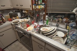 Pile of dirty dishes in sink and counter top after a party