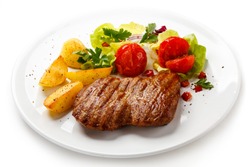 Grilled steak, baked potatoes and vegetable salad