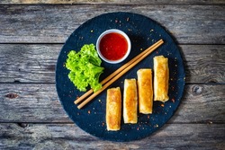 Spring rolls on stone plate on wooden table