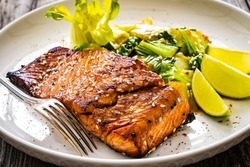Fried teriyaki salmon steak with pak choi and lime on wooden table 