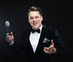 Young man in suit singing over the microphone with energy.