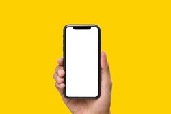 Hand holding the black smartphone with blank screen on yellow colour background