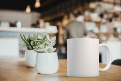 White coffee Mug Mockup set-up in a cafe, next to cactus plants and with blurred background. Great for overlaying your custom quotes and designs for selling mugs.