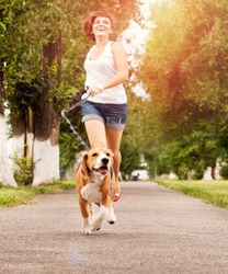 Happy young woman jogging with her beagle dog