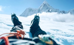 POV shoot of a high altitude mountain climber's lags in crampons. He lying and resting on snow ice field with Ama Dablam (6812m) summit covered with clouds background.Extremal people vacations concept