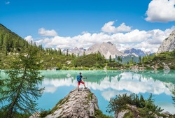 Backpacker with backpack enjoying the turquoise Lago di Sorapiss 1,925m altitude (mountain lake) view as he has mountain walk in Dolomite Mountains, Italy. Active people in nature concept. 