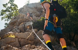 Climbers woman and man in protective helmets and climbing harnesses ascending cliffs on rock wall in Paklenica National park site in Croatia. Active extreme sports time spending concept.