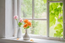 beautiful roses in vases on old wooden windowsill