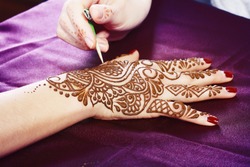 Image detail of henna being applied to hand close up